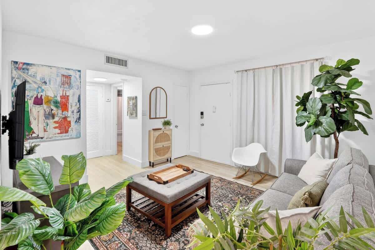 A living room with a sofa, coffee table, and plants.