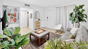 A living room with a sofa, coffee table, and plants.