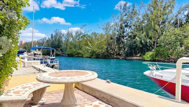 A marina with boats, a water body, and a patio area with tables and chairs.