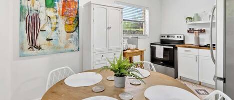 Une cuisine moderne avec des meubles blancs, une table à manger avec des sets de table et un tableau accroché au mur.