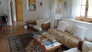 A living room with a sofa, armchair, glass coffee table, and a painting on the wall. - Gadahüs Elvers, Obersaxen-Misanenga, (Obersaxen), 34091B by Interhome (Obersaxen Affeier)