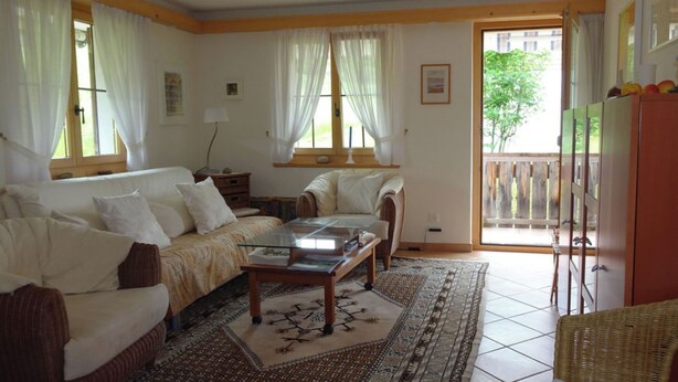 A living room with a sofa, a coffee table, a patterned rug, and a view of the outside. - Gadahüs Elvers, Obersaxen-Misanenga, (Obersaxen), 34091B by Interhome (Obersaxen Affeier)