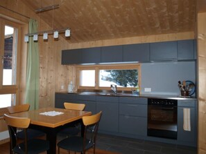 A modern kitchen with a dining area, wooden walls, and a window.