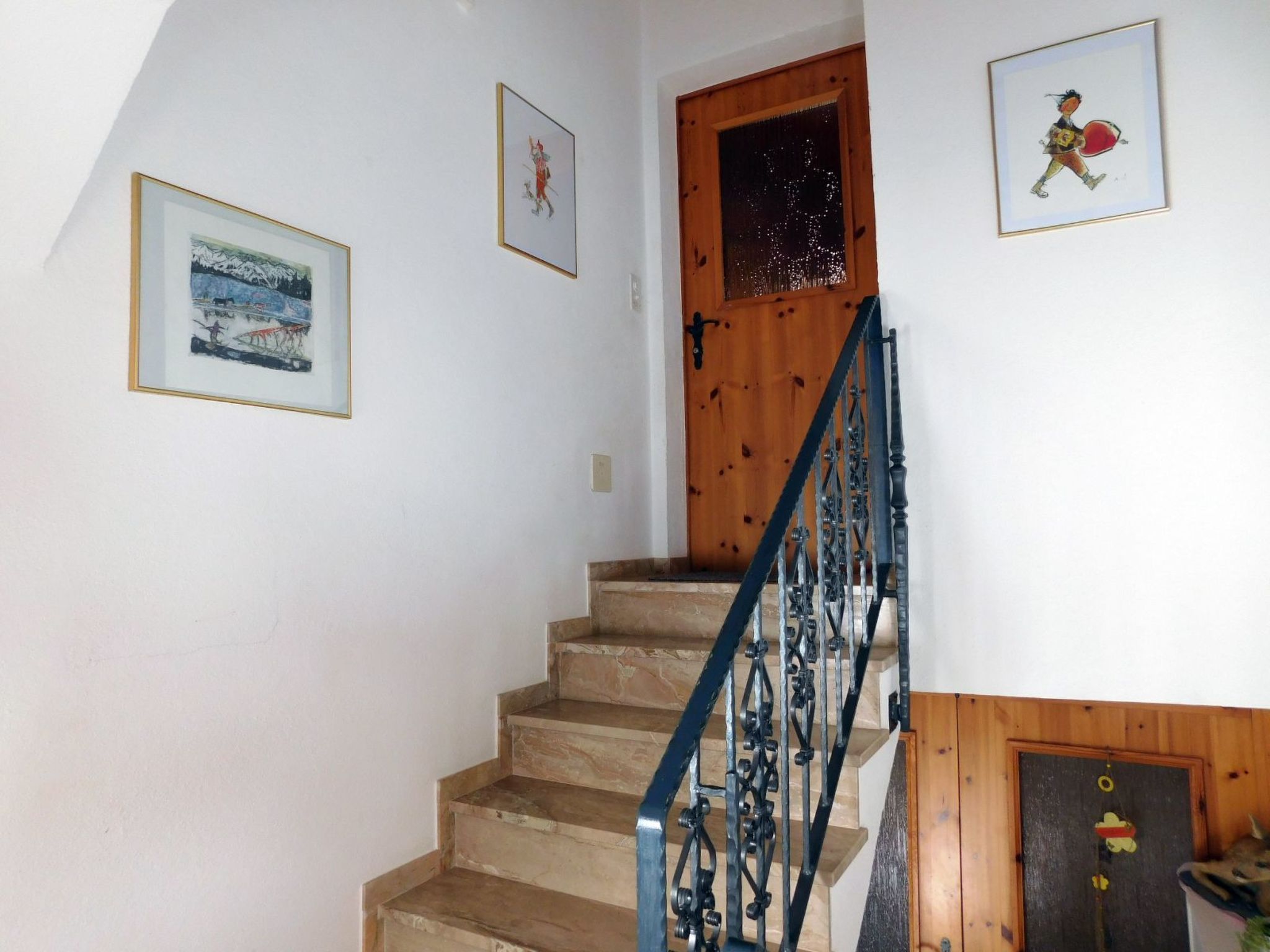Un escalier avec des marches en bois et une rampe en métal, menant à une porte en bois.
