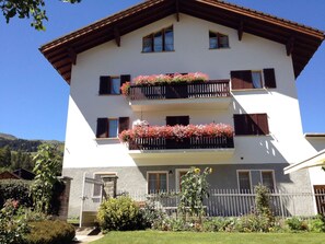 Ein zweistöckiges Gebäude mit Balkonen, einer weißen Fassade und einem Holzdach.