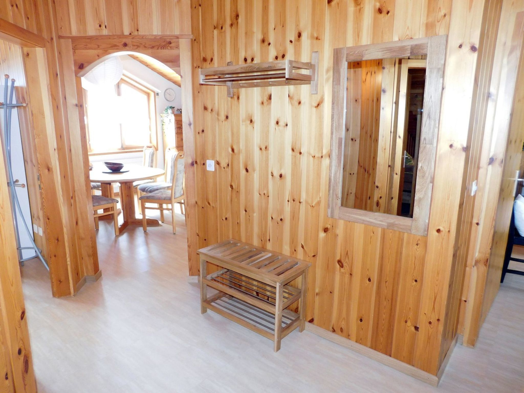 A wooden interior with a dining area, a bench, and a window.
