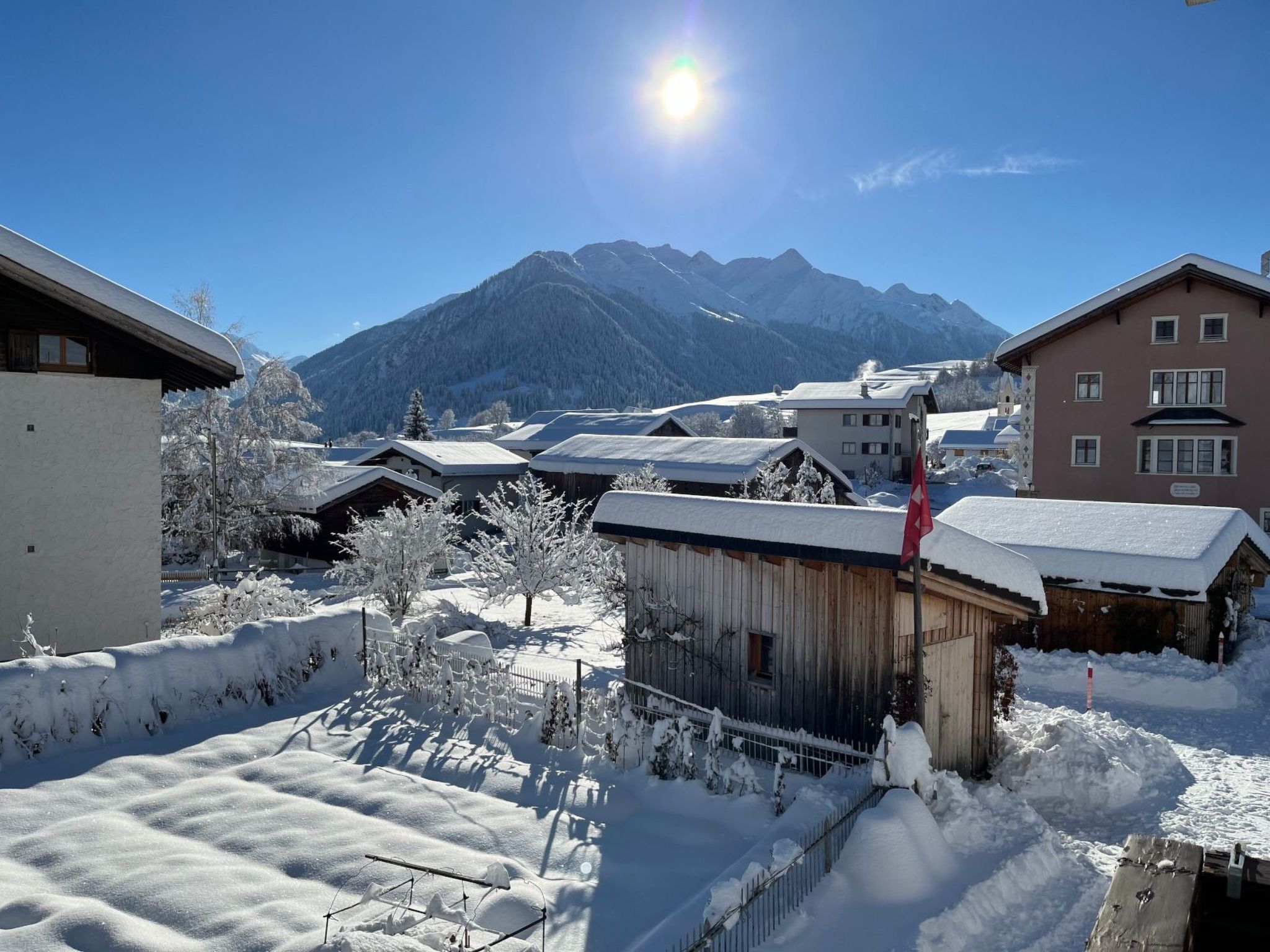 Ein verschneites Dorf mit Gebäuden und Bergen im Hintergrund.