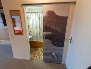 A bathroom with a shower curtain, a mirror, and a tiled floor.