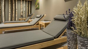 Un cuarto de spa con tres camastros de madera, un reloj de pared y un cuadro de flores.
