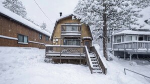En træhytte med balkon, omgivet af sneklædte træer.