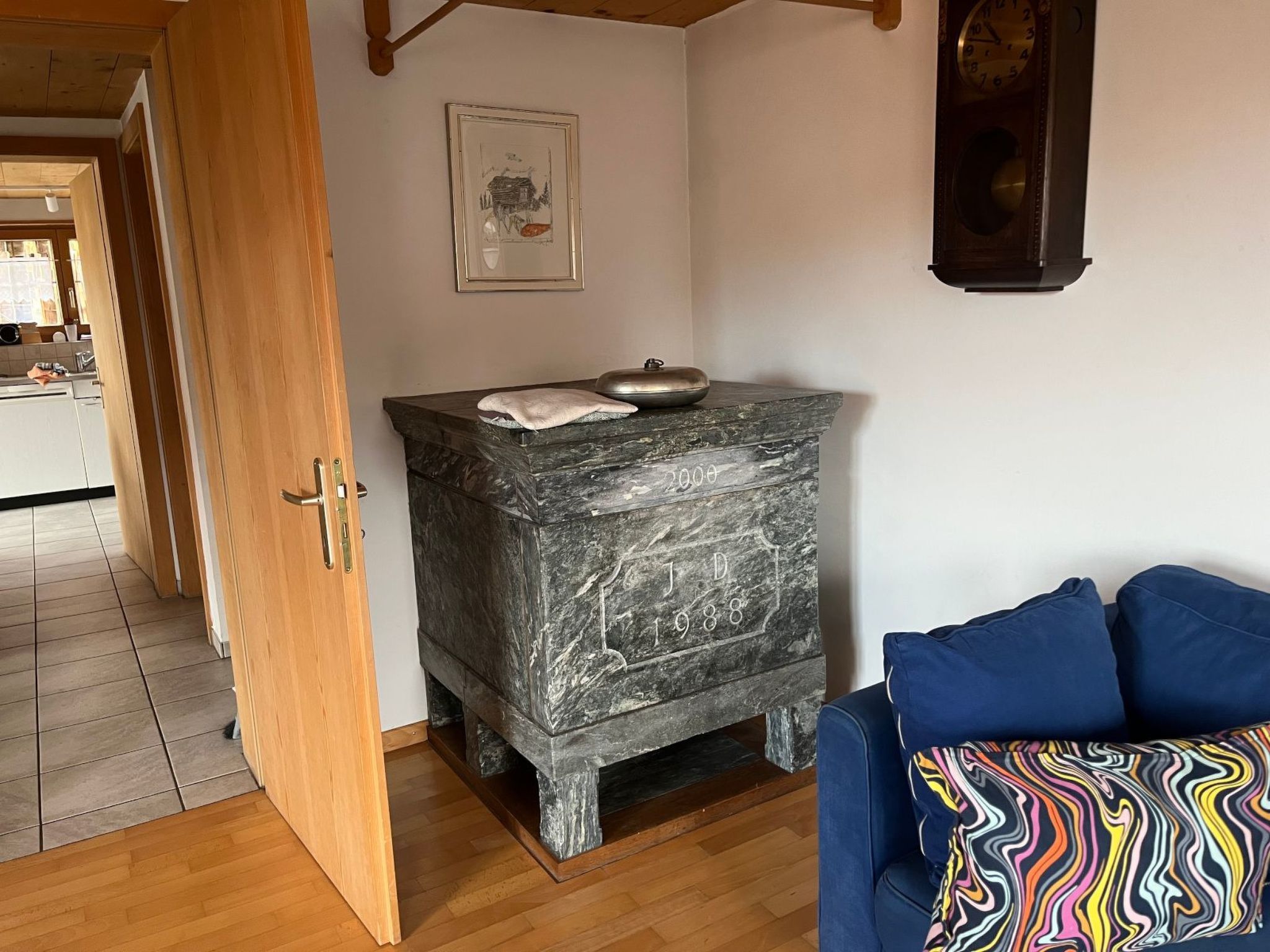 A room with a stone fireplace, a blue sofa, and a wooden door.