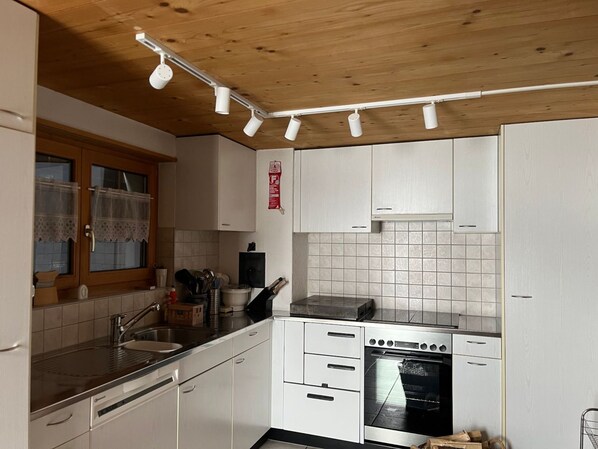 Una cocina moderna con armarios blancos, horno de acero inoxidable y encimera negra.