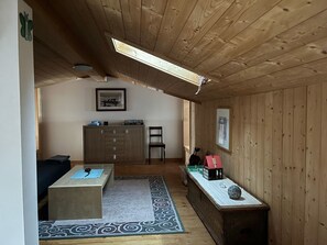 Un interno in legno con un'area pranzo, un divano, un tavolo con un oggetto decorativo e un armadio.