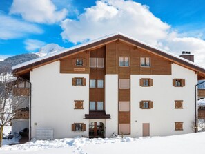 Ein zweistöckiges Gebäude mit geneigtem Dach, Holzläden und einem Schild mit der Aufschrift 'Hotel Caplan'.