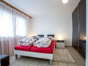 A bedroom with a bed, bedside tables, a nightstand, and a mirror. - Davos Caplan Ledermann, Vella, (Vella), 44006B by Interhome (Vella)