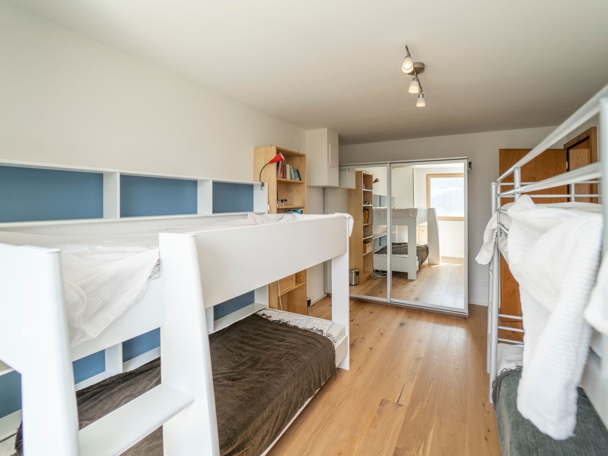 Habitación con literas, un escritorio, una estantería y una ventana.