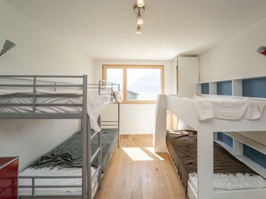 A dormitory room with bunk beds, a window, and a ceiling light.