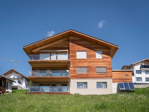 Ein modernes mehrgeschossiges Gebäude mit Holzfassade, großen Fenstern und Balkonen.