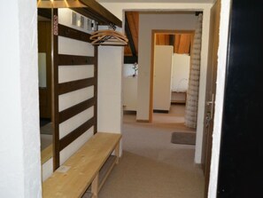 A narrow hallway with a wooden bench, a coat rack, and a door leading to a room with a bed and a window. - Anita 7 Defuns, Brigels, (Breil/Brigels), 65001B by Interhome (Breil/Brigels)