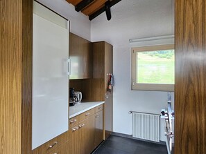 Une cuisine compacte avec des meubles en bois, un plan de travail et une fenêtre donnant sur un paysage verdoyant.