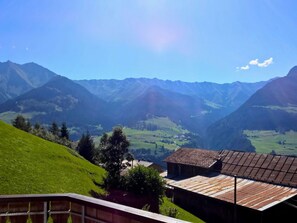 A mountainous landscape with a clear sky, a valley, and a building with a sloped roof. - Residenza Bein, Morissen, (Morissen), 43008B by Interhome (Morissen)