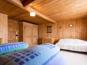 Ein Zimmer mit Holzwänden, zwei Betten, einem Schminktisch und einem Spiegel.