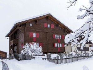 Un bâtiment en bois doté de nombreuses fenêtres et dont le toit est recouvert de neige.