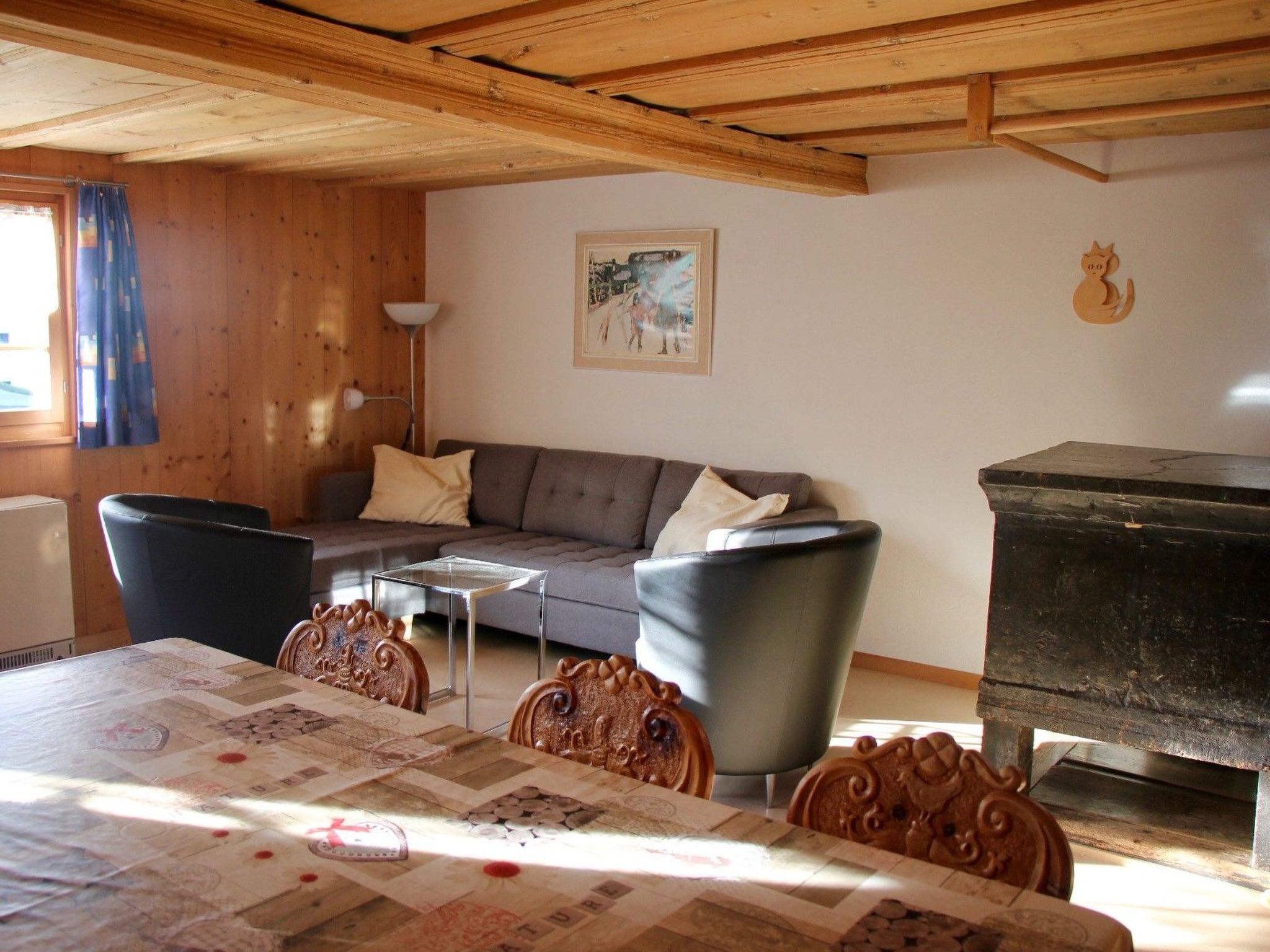 Un salón acogedor con un sofá, sillas, una mesa con colcha, una lámpara y un cuadro en la pared.
