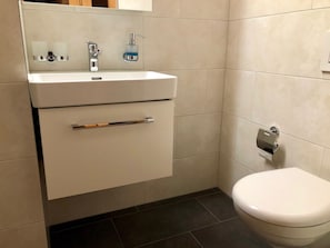 Ein Badezimmer mit einem weißen Waschbecken, einer Toilette und einem Handtuchhalter.