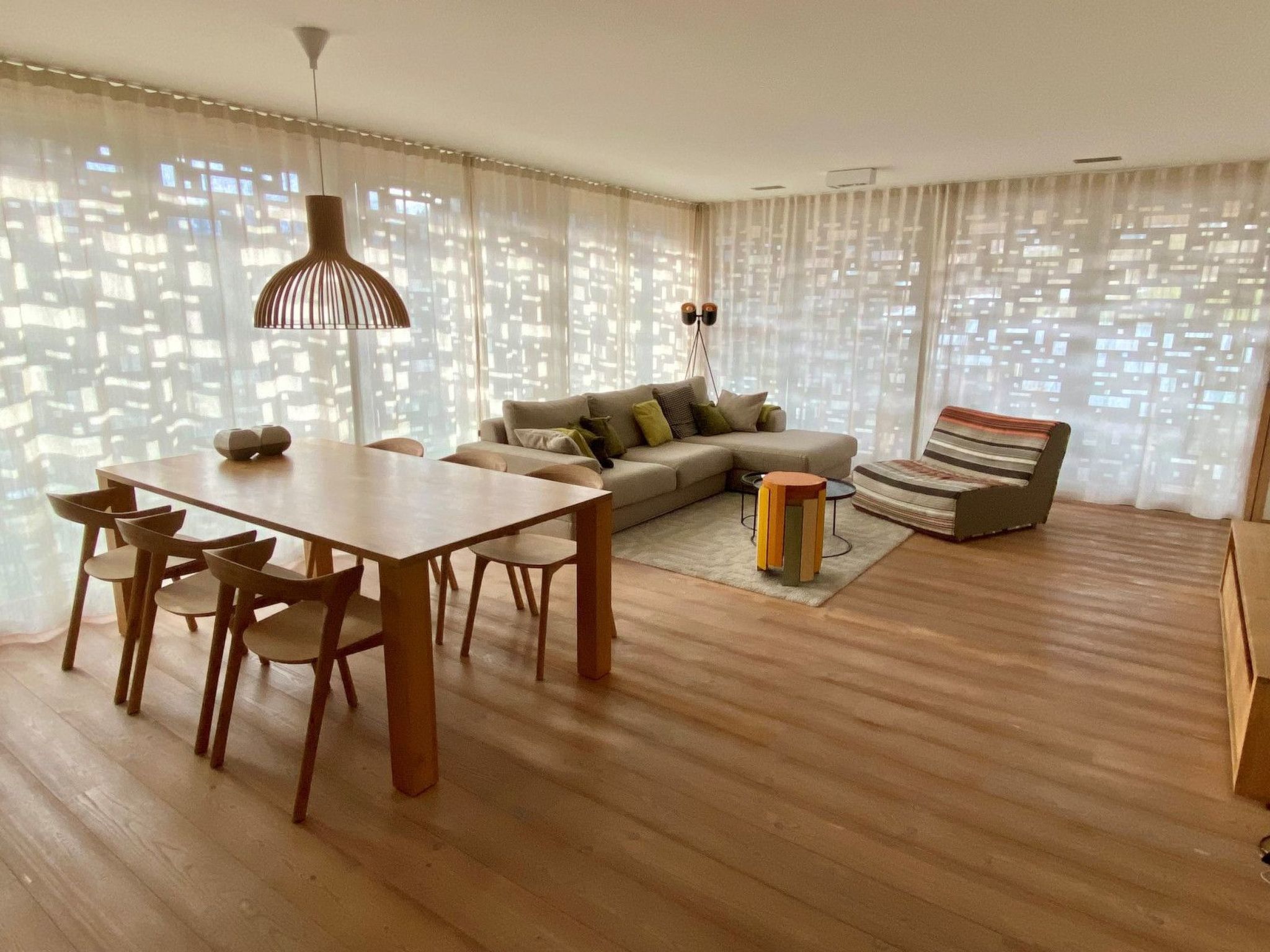 Un salon moderne avec un coin repas, comprenant un canapé, un fauteuil à rayures, une table à manger avec des chaises et un lampadaire.