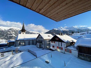 Ein schneebedecktes Dorf mit traditionellen Gebäuden und einem Kirchturm.
