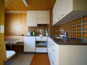A compact kitchen with wooden walls, a built-in oven, and a sink. - Genoveva Sax, Obersaxen-Meierhof, (Obersaxen), 34065B by Interhome (Obersaxen Affeier)
