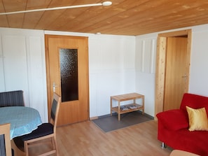 A room with a wooden ceiling, a door with a frosted glass panel, a small wooden table with magazines, a red sofa, and a wooden bench. - Crestas Calzaferri, Brigels, (Breil/Brigels). by Interhome (Breil/Brigels)