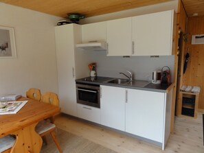 Una cocina compacta con armarios blancos, un lavamanos de acero inoxidable y un horno empotrado.