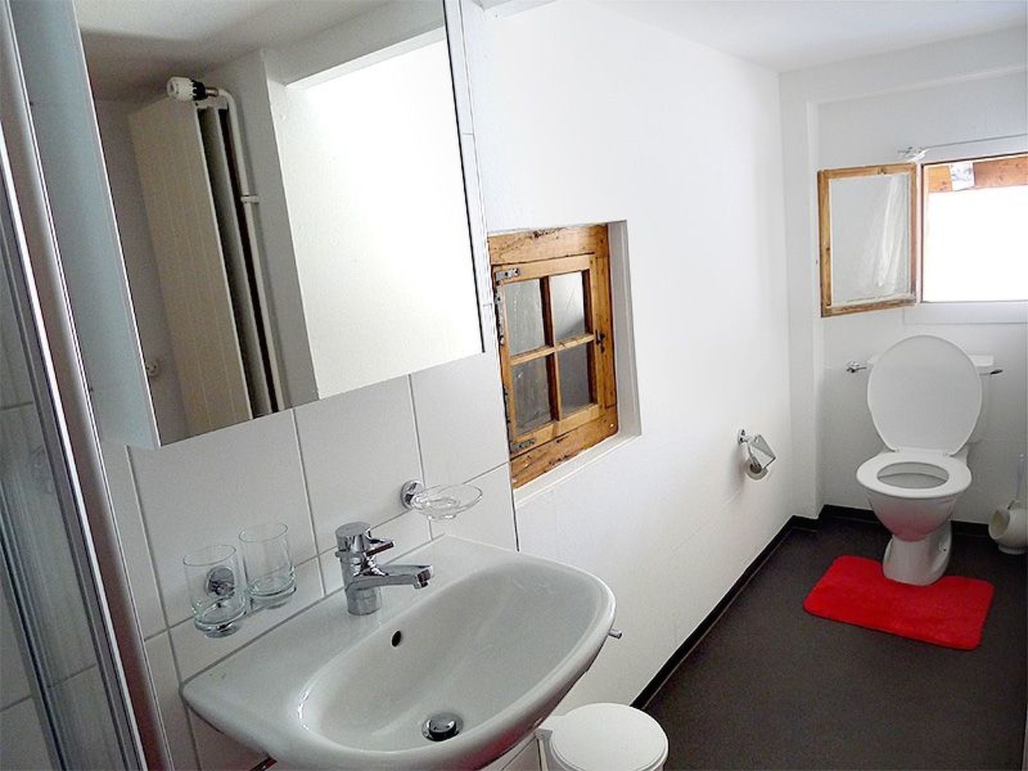 Un bagno con lavandino, specchio e water bianchi.
