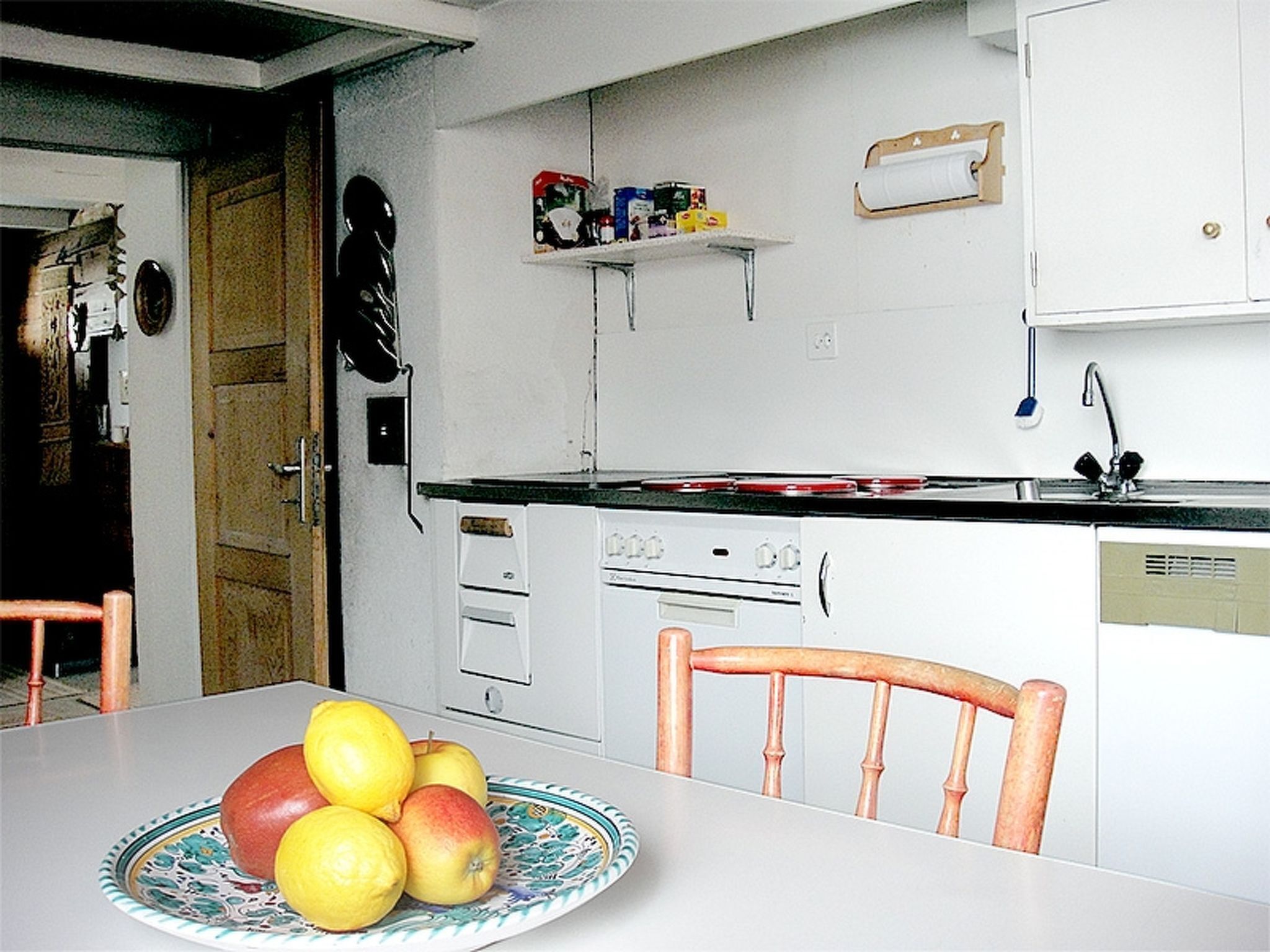 Een koelkast, een oven, een vaatwasser, kookgerei, borden en bestek