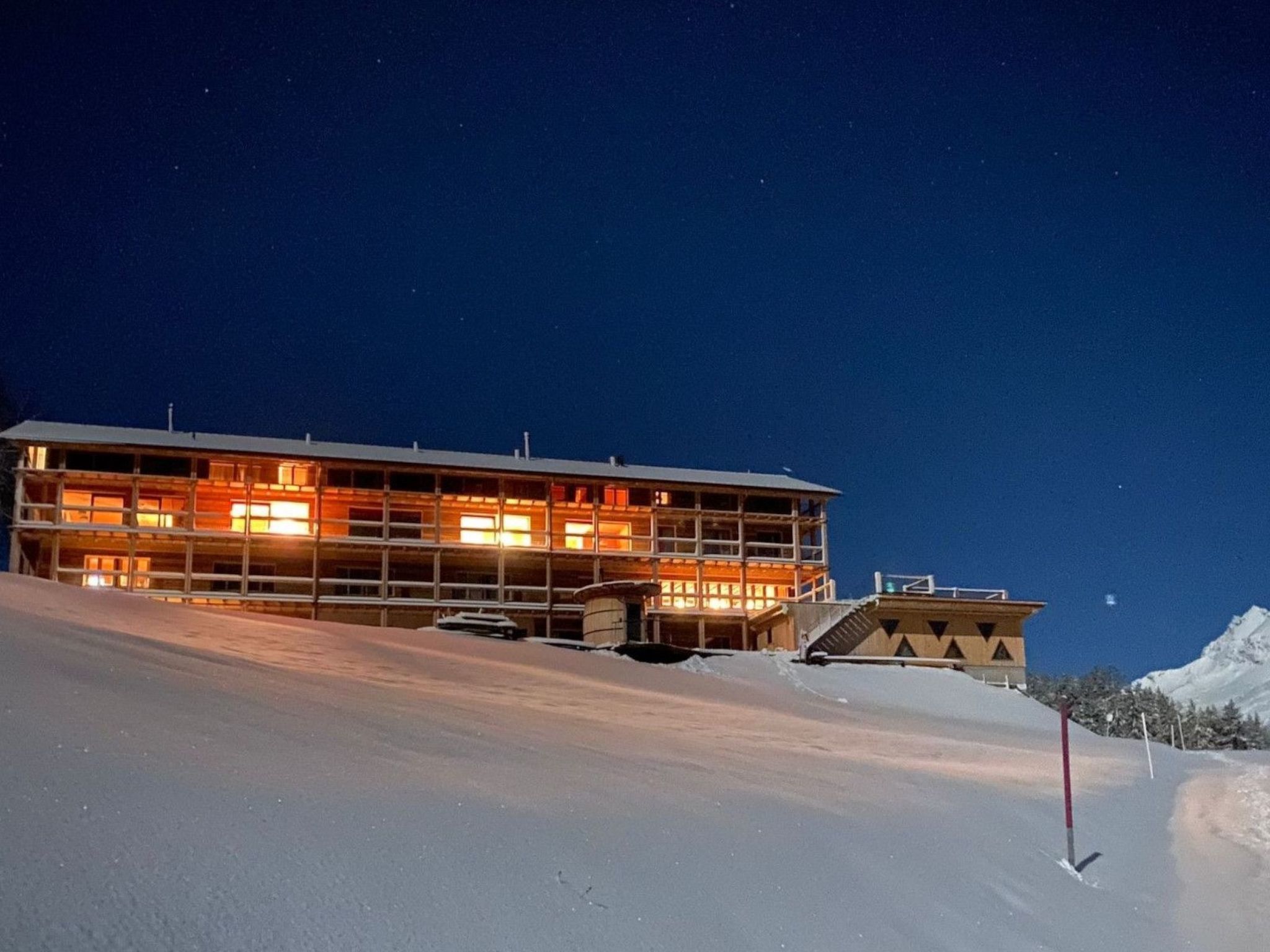 A multi-story building with a ski lift in the background, surrounded by snow.