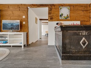 A room with a wooden wall, a television, a chessboard, and a fireplace. - Pacifica und Romantica in Cumpadials, (Cumpadials), 76002B by Interhome (Cumpadials)