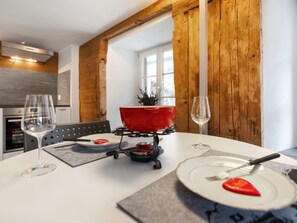 A dining table with a red portable stove, two wine glasses, and plates with food. - Pacifica und Romantica in Cumpadials, (Cumpadials), 76002B by Interhome (Cumpadials)