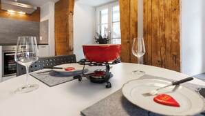 Una mesa de comedor dispuesta con copas de vino, platos y un tazón rojo.