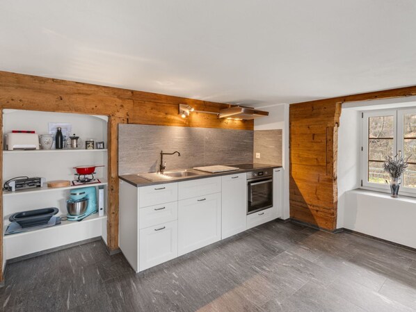 A modern kitchen with white cabinetry, a stainless steel sink, and a built-in oven. - Pacifica und Romantica in Cumpadials, (Cumpadials), 76002B by Interhome (Cumpadials)
