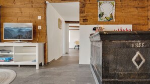 Una habitación con pared de madera, chimenea con diseño de rombos, televisión y estantería.
