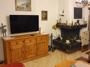 A living room with a large flat-screen TV, wooden cabinet, fireplace, and a red sofa.