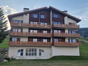Een meerlaags gebouw met balkons, een plat dak en een gazon ervoor.