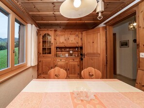 Een houten interieur met een eettafel, stoelen en uitzicht op de omgeving.