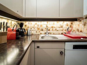 Een keuken met een modern design, voorzien van een roestvrijstalen spoelbak, een koffieapparaat en een afwassysteem.