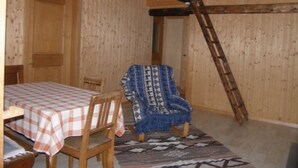 A wooden interior with a dining table set, a patterned rug, and a chair with a blue blanket. - Tegia Veglia / Erlebnisalp Glivers, Sumvitg, (Sumvitg), 75002B by Interhome (Cumpadials)