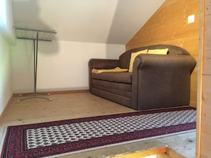 Une pièce avec un canapé marron, un tapis à motifs et un plafond en bois.