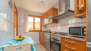 Eine kleine Küche mit Mikrowelle, Backofen und Holzschränken.