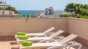Eine Dachterrasse mit Liegestühlen und Meerblick.